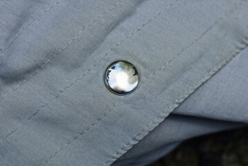 one white frayed metal rivet on a gray garment fabric