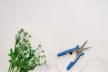 Florist equipment with flowers on wooden background, top view