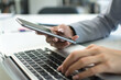 © Bojan - Close up of female hands holding smart phone and typing on laptop keyboard.