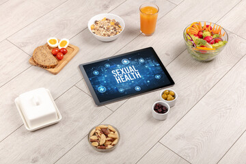 SEXUAL HEALTH concept in tablet pc with healthy food around, top view