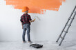 © Andrii Lysenko - boy wearing a protective orange hard hat paints the wall.