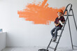 © Andrii Lysenko - boy dressed in protective orange sits on a construction ladder. Copy space.