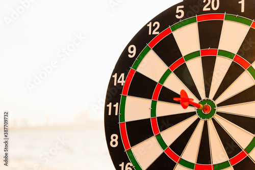 Closeup the dart arrow hit center on Bullseye(bull\'s-eye) of a dartboard is a target of challenge business, strategy marketing target, objective financial and goal a concept