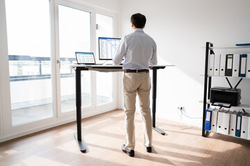 man working on computer at standing desk
