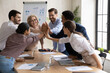Overjoyed diverse businesspeople five high five motivated for shared business victory success or win at meeting. Happy excited employees engaged in teambuilding activity in office. Teamwork concept.