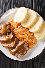 Canvas Print - Roasted Pork, Dumplings and Sauerkraut Vepro knedlo zelo close-up in a plate on the table. Vertical top view from above