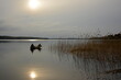 © Svetlana Ievleva - Two fishermen fishing from a boat in lake center. Sun shining from misty clouds and reflect in water.