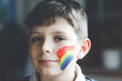© Irina Schmidt - Portrait of adorable school kid boy with painted rainbow with colorful colors on face. Lonely child during pandemic coronavirus quarantine. Children make and paint rainbows around the world