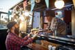 © luckybusiness - caucasian beardy hipster taking two sandwiches from polite female afro-american employee in fast food service