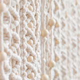 Fototapeta Do akwarium - Close-up of hand made macrame texture pattern. Eco friendly modern knitting. Natural decoration concept in the interior. Handmade macrame wall hanging 100% cotton and wooden beads. Soft focus