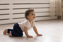 Cute Small African American Toddler Baby Child Crawl On Warm Wooden Home Floor. Smiling Little Biracial Infant Kid Play In Children Room Indoors, Explore World. Childcare, Upbringing Concept.