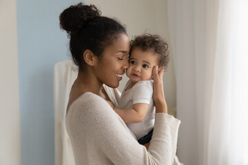 happy young african american mom hold in hands hug cute little ethnic baby toddler show love care. s