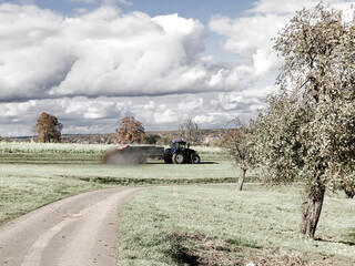 tractor throwing cow manure on a meadow in autumn in Germany