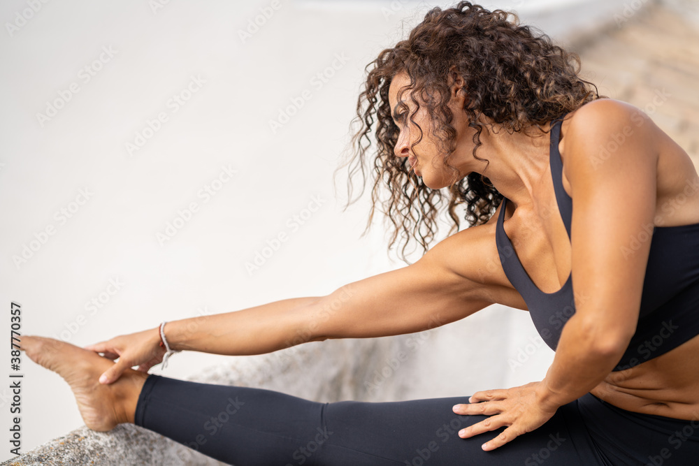 Middle-aged woman with fitness body working out on the terrace of her house - obrazy, fototapety, plakaty 