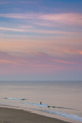 Canvas Print - lone fisherman in the surf at a wild and empty beach during a beautiful sunrise