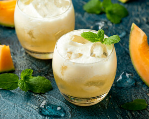 Wall Mural - Refreshing Cantaloupe Melon cocktail with ice and mint on rustic table