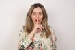 © Jihan - Dont tell my secret or not speak too loud, please! Emotional surprised student makes hush gesture, asks be quiet, has scared expression as afraids of revealing secret, poses against gray studio wall.