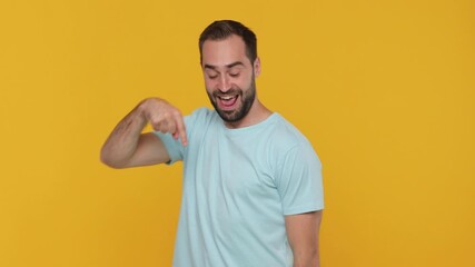 Canvas Print - Fun expressive young man 20s years old in basic casual blue t-shirt look camera pointing fingers hands down on copy space workspace area isolated on yellow background studio. People lifestyle concept