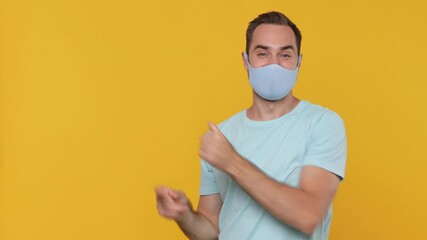 Sticker - Young man in blue t-shirt sterile black face mask denim white shirt pointing on workspace promo area isolated on yellow background studio. Pandemic coronavirus 2019-ncov sars covid-19 virus concept