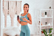© HBS - Female fitness trainer with bottle of capsules in hands at home.