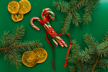 Christmas or New Year decorations background. Branches of a Christmas tree and candies on a green background. Top view with copy space.