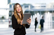 © Minerva Studio - Smiling businesswoman using a digital tablet outdoor