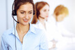 © rogerphoto - Call center operators. Focus on beautiful business woman using headset in sunny office