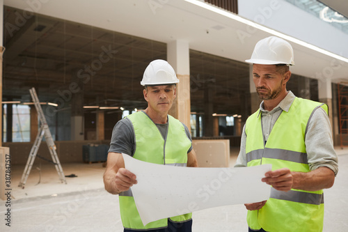 Fotografía Waist up portrait of two professional building contractors looking at plans whil