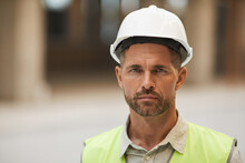 Close Up Portrait Of Mature Construction Worker Wearing Hardhat And Looking At Camera While Standing At Construction Site, Copy Space