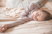 Female Child Lies On Pillow In Bed In Bedroom At The Motning. Girl Enjoys Bedtime.