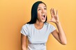 © Krakenimages.com - Beautiful hispanic woman wearing casual white tshirt shouting and screaming loud to side with hand on mouth. communication concept.