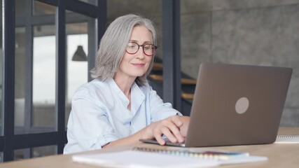 Wall Mural - smiling professional mature business woman wears glasses using laptop computer sits at workplace des