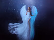 Fantasy woman angel soars in the air with white huge bird wings. Ghost girl in levitation flies. Dark night background, magical light. Lady goddess in white dress, fabric waving fluttering in motion.