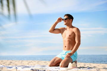 Wall Mural - Happy man with slim body resting on beach. Space for text