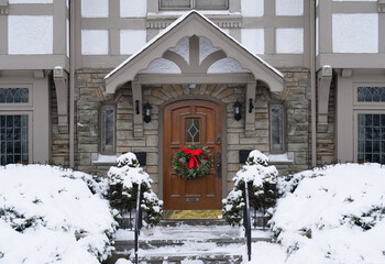 Poster - Old fashioned Tudor style house with Christmas wreath on front door and snow covered bushes