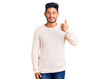 © Krakenimages.com - Handsome latin american young man wearing casual winter sweater smiling happy and positive, thumb up doing excellent and approval sign