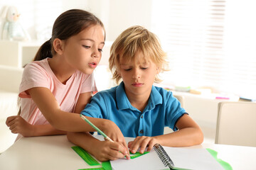 Poster - Little boy and girl doing homework at table indoors