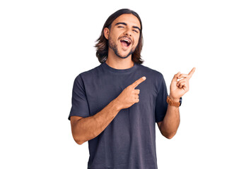 Young handsome man wearing casual clothes smiling and looking at the camera pointing with two hands and fingers to the side.