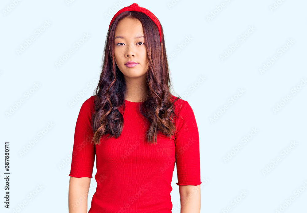 Young beautiful chinese girl wearing casual clothes and diadem with serious expression on face. simple and natural looking at the camera.