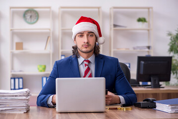 Wall Mural - Young male employee working in the office at Christmas Eve