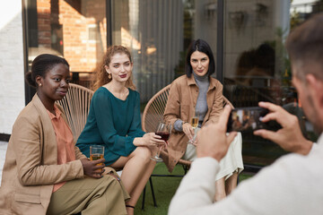 Wall Mural - Portrait of three elegant women posing for photo and smiling at camera while enjoying outdoor party at terrace, copy space