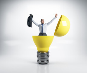 Wall Mural - Happy businessman sitting in a big yellow light bulb.