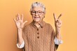 © Krakenimages.com - Senior grey-haired woman wearing casual clothes and glasses showing and pointing up with fingers number seven while smiling confident and happy.