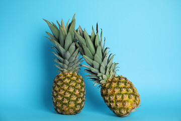 Ripe juicy pineapples on light blue background