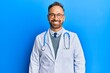 © Krakenimages.com - Handsome middle age man wearing doctor uniform and stethoscope with a happy and cool smile on face. lucky person.