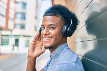 Young african american man listening to music using headphones at the city.