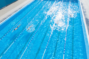 People training in outdoor swimming pool on sunny day