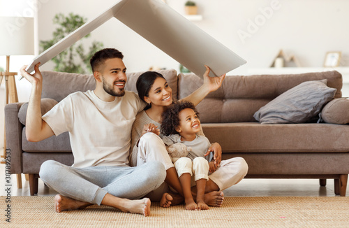 Happy multiethnic family under fake roof in living room.