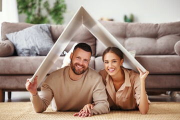 Wall Mural - concept housing  young family couple.  man and woman under fake roof in  new home