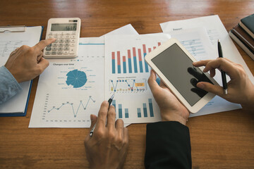 Two businessmen are working analyzing the company annual budget and using digital tablet to find information data result.